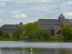 The abbey, seen from the other side of a lake. It's a bunch of huge building of grey slab roofs and red bricks.